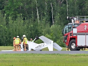 A small plane lies inverted with firefighters and a fire truck next to it