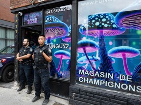 Two police stand guard outside Funguyz, a storefront advertising magic mushrooms