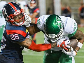 Alouettes' Tyrice Beverette reaches over to Roughriders' Tevin Jones to grab the football he's holding