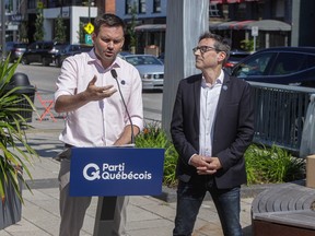 A man speaks behind a podium on a city street as another man stands next to him