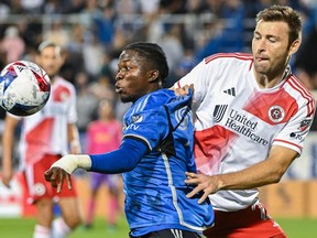 CF Montréal's Kwadwo Opoku, in Montreal’s home blue uniforms, keeps his eyes on the ball while beign challenged by the Revolution's Dave Romney during second-half action at Stade Saputo last Saturday.