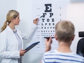Female optometrist taking eye test of young patient in ophthalmology clinic