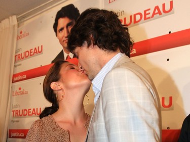 Justin Trudeau kisses Sophie Grégoire Trudeau in front of a wall of campaign signs