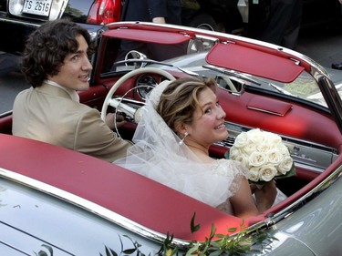 Justin Trudeau and Sophie Grégoire Trudeau, in wedding attire, look back while seated in a vintage convertible