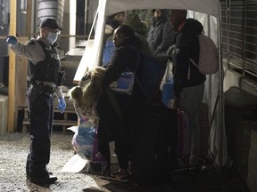 An RCMP officer instructs asylum seekers as they wait for processing after crossing the border at Roxham Road from New York into Canada, Friday March 24, 2023, in Champlain, N.Y. The closure of a rural southern Quebec road used by thousands of asylum seekers to enter Canada from the United States hasn't stopped would-be refugees from arriving, federal data shows.