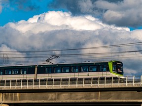 Photo of large clouds in the sky as an elevated train passes over a stretch of track