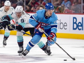 Canadiens' Juraj Slafkovsky, seen in last season's light-blue jerseys, skates away from Kraken's Ryan Donato during game at the Bell Centre in January.