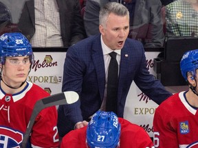 Canadiens head coach Martin St. Louis, wearing a blue blazer, black tie and white shirt, leans over the bench to talk to his players last season.