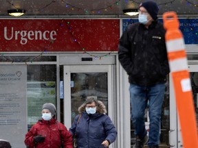 People are seen leaving a hospital emergency room wearing masks in the winter.