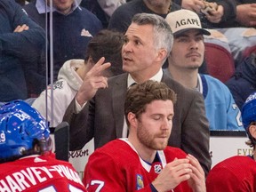 Canadiens head coach Martin St. Louis, wearing a brown sports jacket, raises two fingers toward an unseen assistant coach while behind the Habs bench last season.
