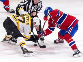 Bruins player in white faces off against Habs player in red as linesman prepares to drop the puck at the Bell Centre.