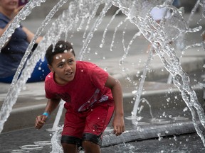 A child ducks from water in a fountain.