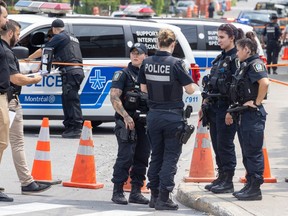 Police officers gather around orange cones and crime scene tape