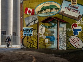 A cyclist comes around the corner next to a mural featuring Montreal icons: Farine Five Roses, Champlain Bridge, the Expos logo and others.