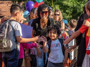 A child and their mother are greeted by older children with balloons and high-fives.