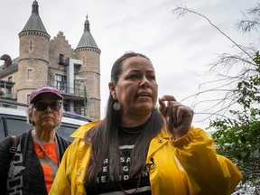 A Mohawk woman in a yellow jacket gestures with the former Royal Victoria Hospital behind her