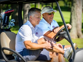 Canadiens head coach Martin St. Louis, in a white shirt in the foreground, shares a golf cart with general manager Kent Hughes, wearing a baseball hat and sunglasses, at the team's annual golf tournament in Laval last year.