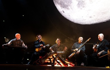 Peter Gabriel, left, opens his concert with a campfire-style introduction to the band as he performs at the Bell Centre in Montreal, on Wednesday, September 13, 2023.