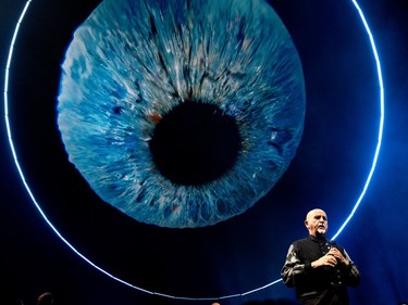Peter Gabriel stands in front of a huge visual of a blue eyeball