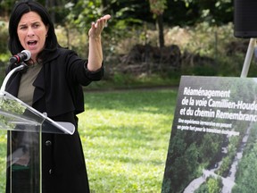 Montreal Mayor Valérie Plante points to a sign as she stands on a green space in front of a lectern.