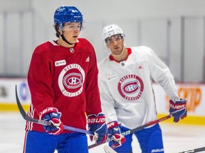 Canadiens' David Reinbacher, left, in a red jersey, and Logan Mailloux, in white, are seen with sticks in their hands at practice last week in Brossard.