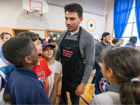 Nick Suzuki, wearing an apron, talks to a crowd of children.
