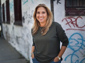 Montreal author and journalist Toula Drimonis stands in front of a graffiti-marked building in Montreal.