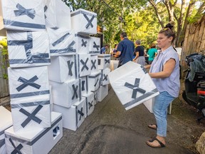 A woman stacks white boxes that will be used as winter shelters for feral cats.
