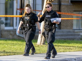 Two female police officers walk past crime-scene tape.