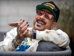 AJ McLean of the backstreet boys is smiling at the camera with his hands together.