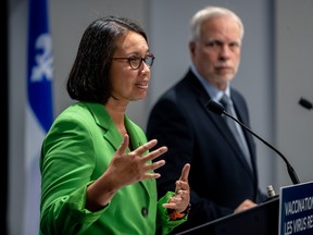 A woman and man speak in front of the Quebec flag at a news conference.