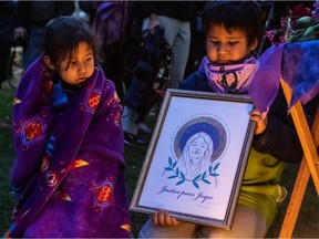 Two young children hold a framed drawing of Joyce Echaquan.