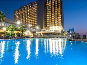 The Hilton hotel with lit, golden windows reflected in the swimming pool.