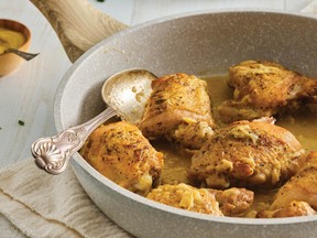 Roasted garlic dijon chicken in a frying pan with a silver spoon resting at the edge.