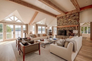 The family room at the Estrie property overlooks the lake and has a fireplace and exposed ceiling beams.
