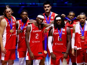 Canadian players, clead in their red uniforms, pose with their bronze medals at the FIBA Basketball World Cup.