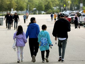 A family of four, seen from behind, walk through a parking lot toward an evacuation centre.