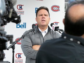 Jeff Gorton answers journalists' questions with his arms crossed at a microphone in front of a Canadiens backdrop