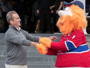 Canadiens owner Geoff Molson and mascot Youppi, dressed in a Habs jersey, hold hands at the team's golf tournament in Laval on Monday.