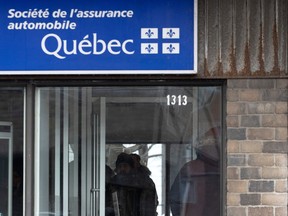 A sign for Quebec's SAAQ is seen in this image. It's blue with white writing, and there's brick siding on the building beside it.