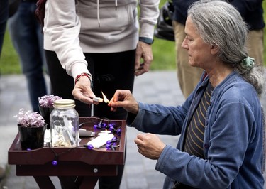 A woman lights candles for people at a small table.