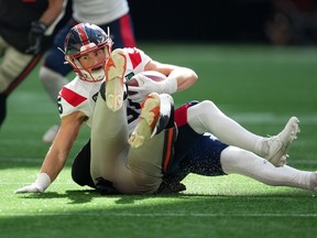 Alouettes receiver Tyler Snead is seen holding the ball on top of Lions' Isaiah Messam, who had tackled him.