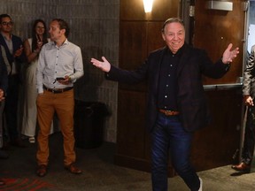 François Legault extends his arm as he enters a room while in casual dress