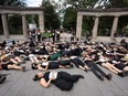 People, many wearing black, lie on the sidewalk outside McGill's Roddick Gates.