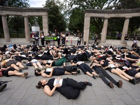 People, many wearing black, lie on the sidewalk outside McGill's Roddick Gates.