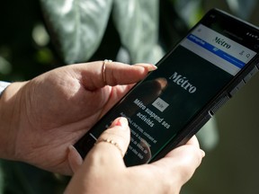 The head of Métro Média says the Quebec newspaper publisher will enter bankruptcy protection this week, ending for good its coverage of local government in parts of the province's two largest cities. A person holds a phone displaying the home page of Métro Média, which reads in French the company is suspending activities.