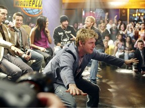 Nick Carter squats and extends his arms as his bandmates sit during an interview at MusiquePlus