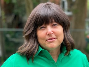 A woman in a green shirt is seen in front of an outdoor background.