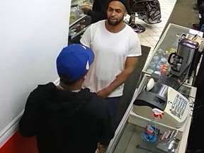 Security footage of two men in front of a counter at a barbershop.