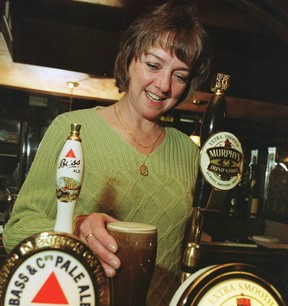 Teresa Slevin holds a pint of beer behind the bar
